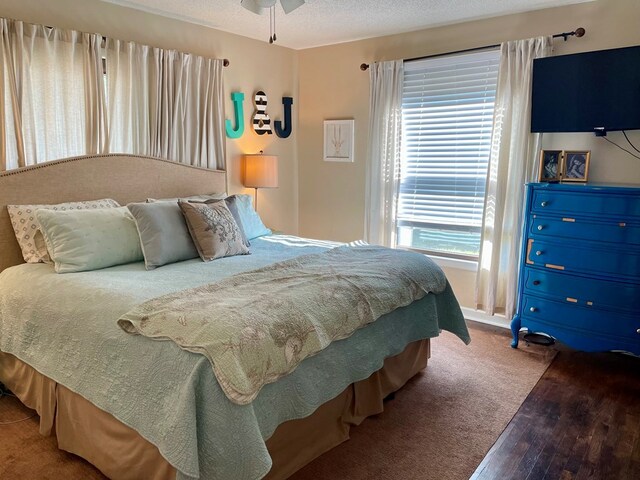 bedroom with a textured ceiling, wood-type flooring, and ceiling fan