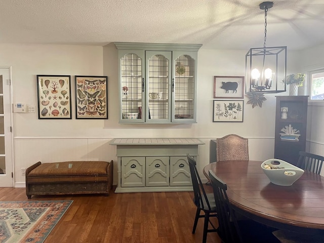 dining room with dark hardwood / wood-style flooring, a chandelier, and a textured ceiling