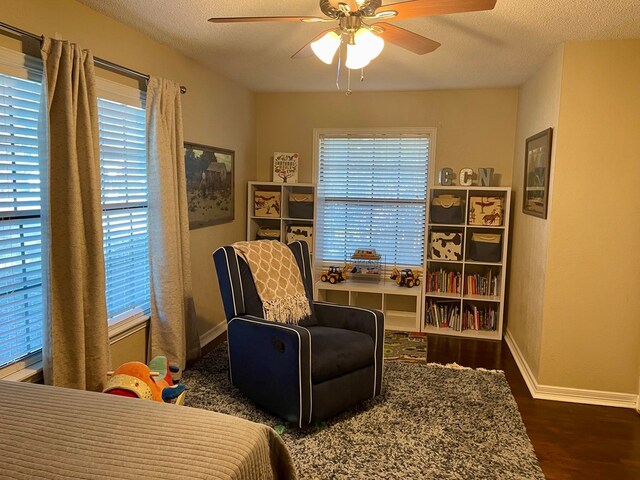 living area with ceiling fan, a textured ceiling, and dark hardwood / wood-style flooring