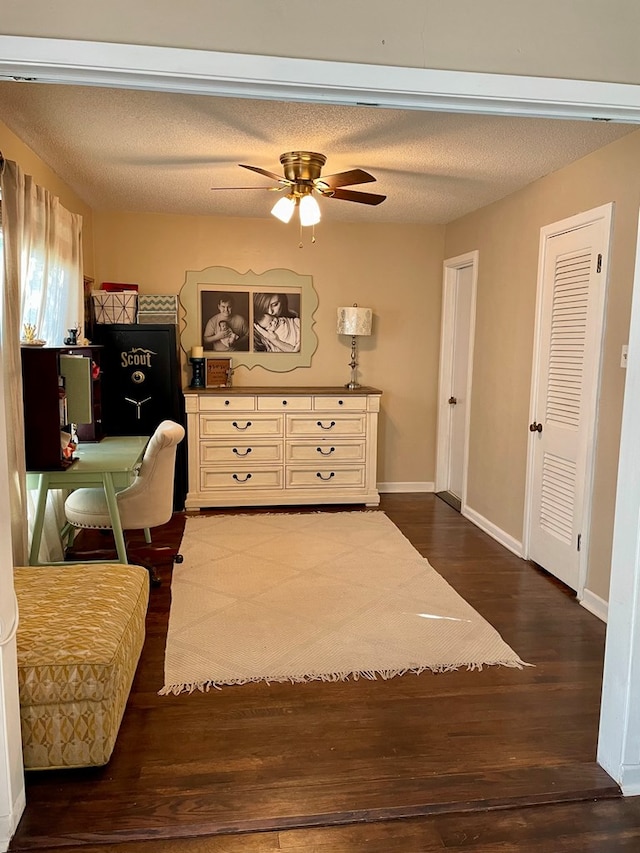 sitting room with ceiling fan, dark wood-type flooring, and a textured ceiling