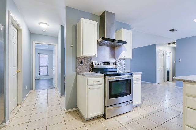 kitchen with visible vents, stainless steel range with electric stovetop, wall chimney exhaust hood, light tile patterned floors, and decorative backsplash