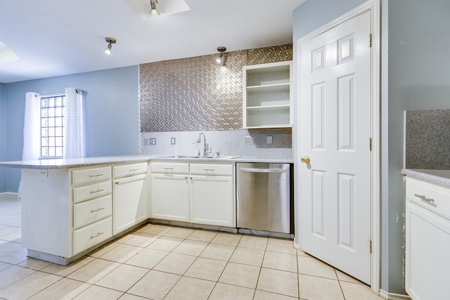 kitchen with a peninsula, light tile patterned flooring, a sink, light countertops, and stainless steel dishwasher