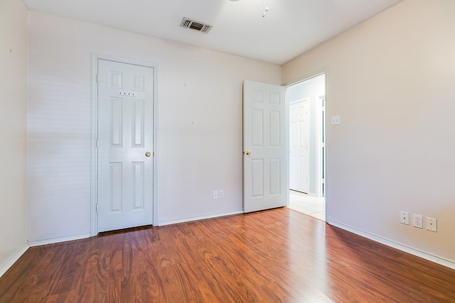 unfurnished bedroom featuring wood finished floors, visible vents, and baseboards