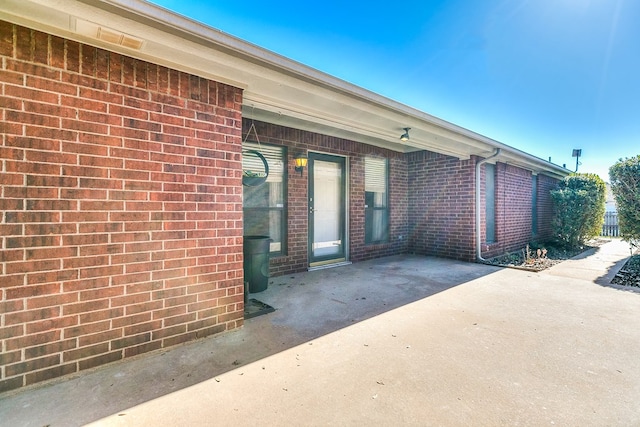 property entrance with brick siding and a patio area