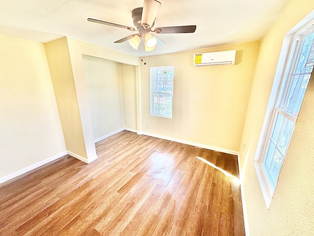 empty room with a wall mounted air conditioner, light hardwood / wood-style floors, and ceiling fan