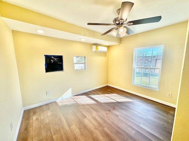 unfurnished room with hardwood / wood-style floors, a wall mounted air conditioner, and ceiling fan