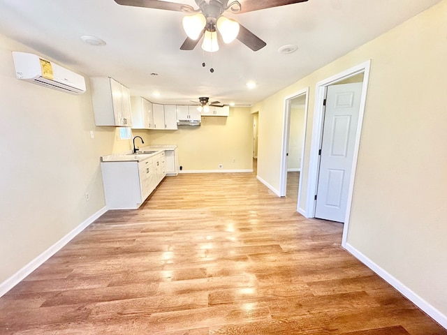 kitchen featuring sink, ceiling fan, a wall mounted air conditioner, light hardwood / wood-style floors, and white cabinets