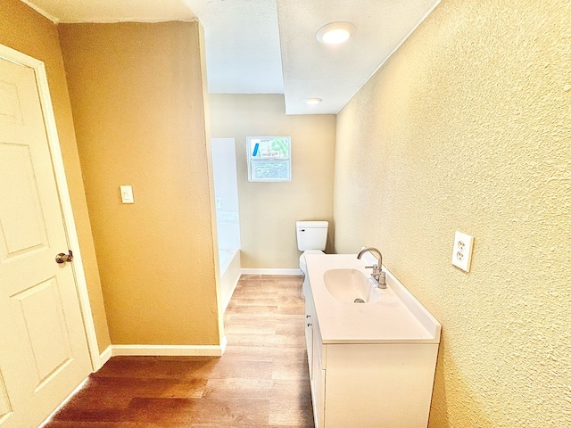 bathroom featuring vanity, hardwood / wood-style flooring, a tub, and toilet