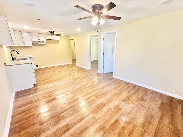 unfurnished living room featuring ceiling fan, sink, and light wood-type flooring