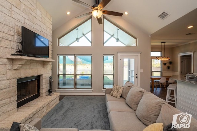 living area featuring lofted ceiling, a fireplace, visible vents, and a wealth of natural light