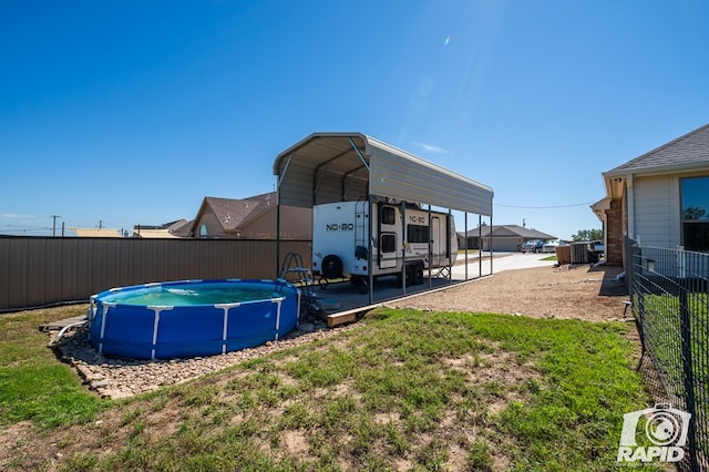 view of outbuilding with a fenced in pool, fence, and a carport