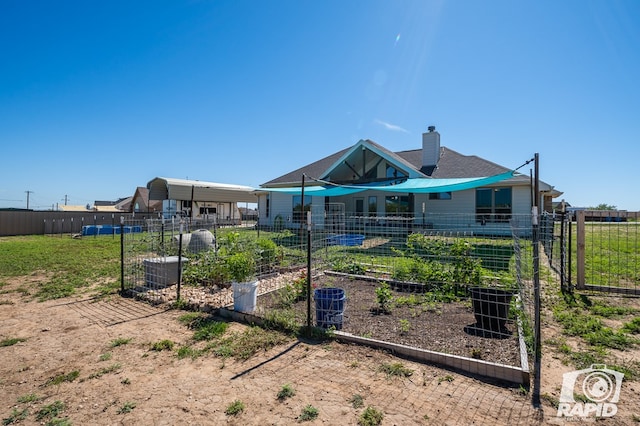 exterior space featuring a chimney, fence, and a vegetable garden