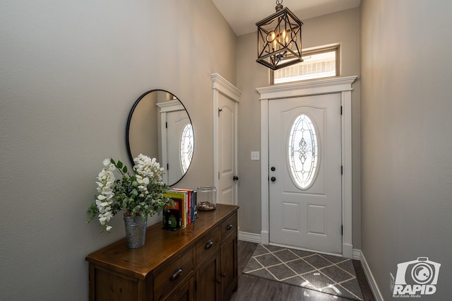 foyer entrance featuring dark wood-style floors, baseboards, and a chandelier