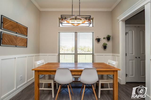 dining area with a wainscoted wall, ornamental molding, a decorative wall, and dark wood-style flooring