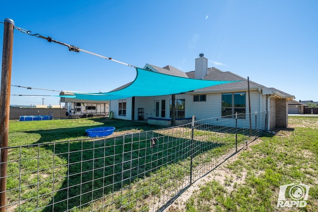 rear view of property featuring a lawn, a chimney, and fence