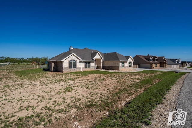 view of front of home featuring stone siding, a chimney, an attached garage, and fence