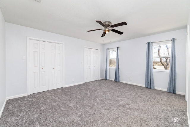 unfurnished bedroom with multiple windows, carpet, two closets, and ceiling fan