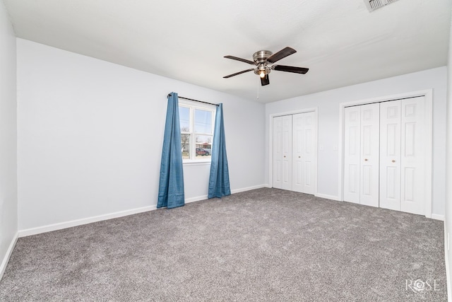 unfurnished bedroom featuring carpet, two closets, and ceiling fan