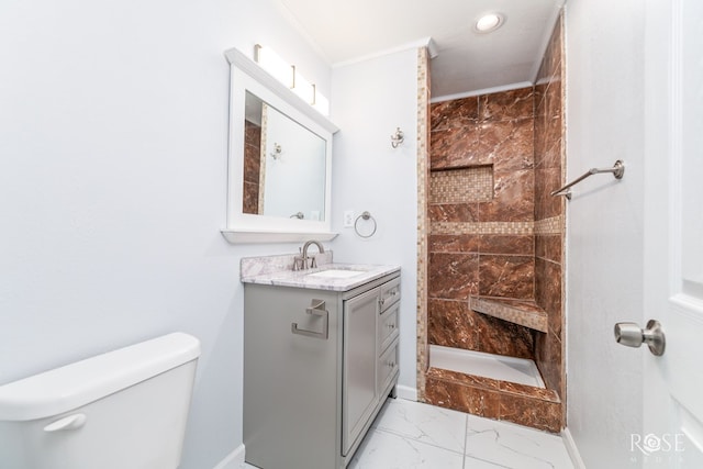 bathroom with a tile shower, vanity, ornamental molding, and toilet