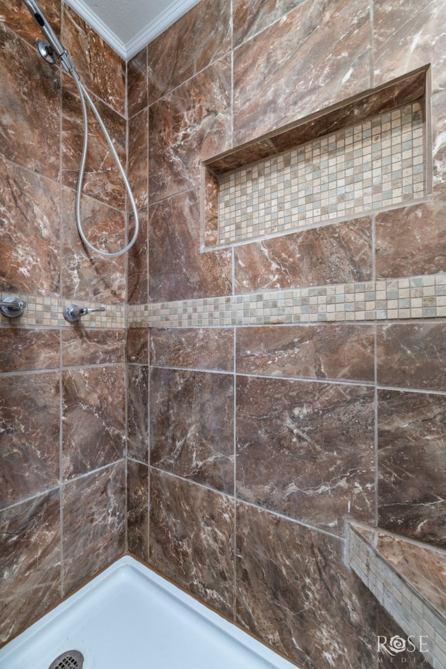 bathroom with ornamental molding and tiled shower