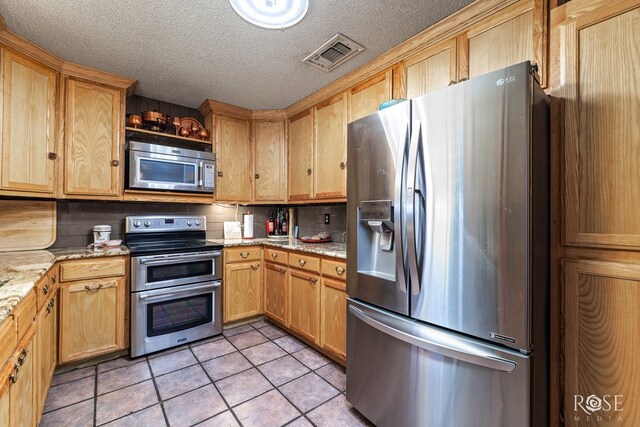 8126 N Fm 2288, San Angelo, TX 76901 - kitchen with stainless steel appliances, light tile patterned floors, a textured ceiling, light stone countertops, and light brown cabinets