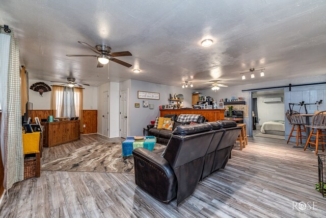 8126 N Fm 2288, San Angelo, TX 76901 - living area featuring ceiling fan, a barn door, a wall unit AC, wood finished floors, and wainscoting