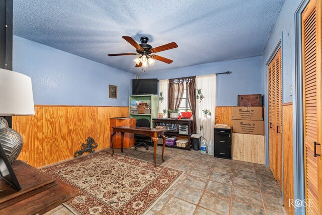 8126 N Fm 2288, San Angelo, TX 76901 - office area featuring wood walls, a ceiling fan, wainscoting, a textured ceiling, and stone finish flooring