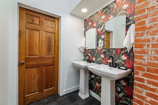 bathroom with brick wall and dual sinks