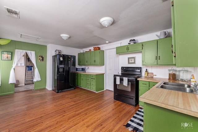 kitchen with sink, black appliances, dark hardwood / wood-style floors, and green cabinets