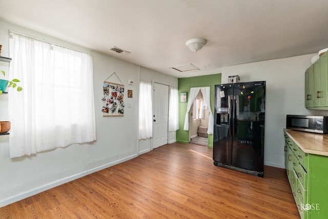 kitchen with black fridge, light hardwood / wood-style floors, and green cabinets