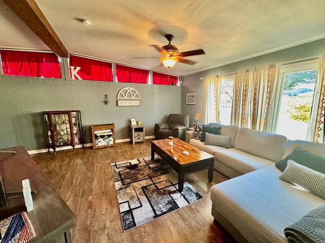 living room featuring hardwood / wood-style floors, a textured ceiling, beamed ceiling, and ceiling fan