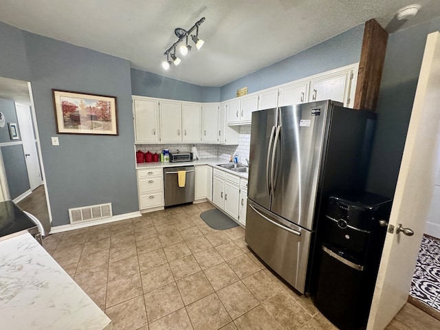 kitchen with light tile patterned flooring, sink, stainless steel appliances, decorative backsplash, and white cabinets