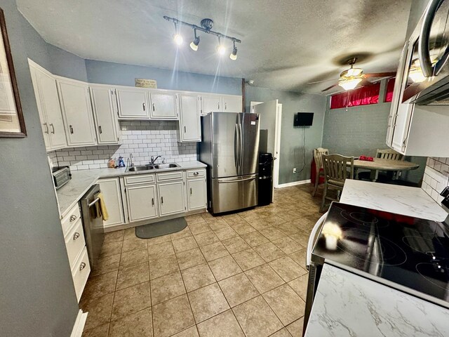 kitchen with tasteful backsplash, sink, white cabinets, ceiling fan, and stainless steel appliances