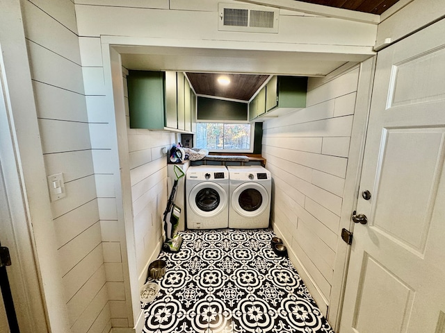 washroom with cabinets, wooden ceiling, washing machine and dryer, and wood walls