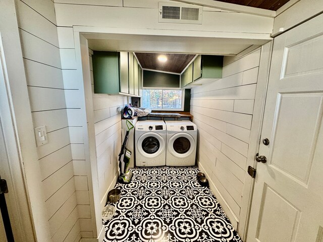 washroom with cabinets, wooden ceiling, washing machine and dryer, and wood walls