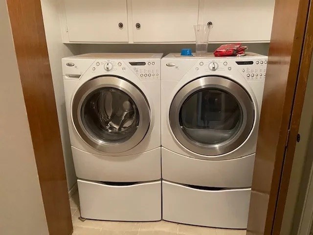 washroom featuring light tile patterned floors, washing machine and dryer, and cabinets