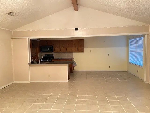 kitchen featuring light tile patterned floors, electric range oven, vaulted ceiling with beams, a textured ceiling, and kitchen peninsula