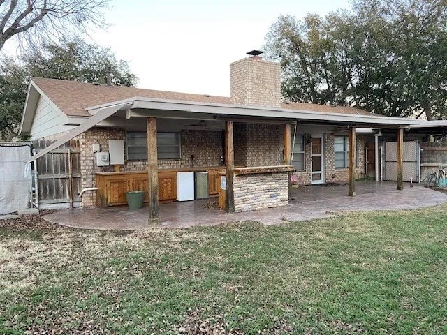 rear view of house featuring an outdoor bar, a patio area, and a lawn