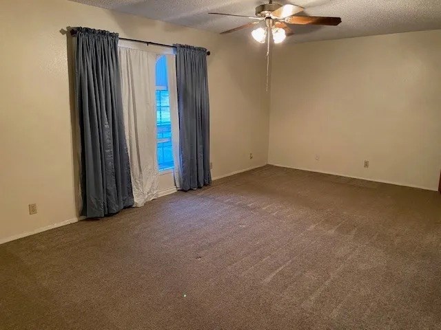 carpeted spare room featuring ceiling fan and a textured ceiling