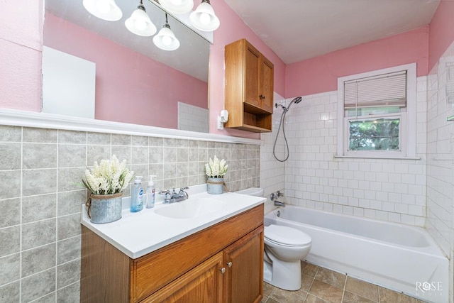 full bathroom featuring tiled shower / bath, tile walls, vanity, and toilet