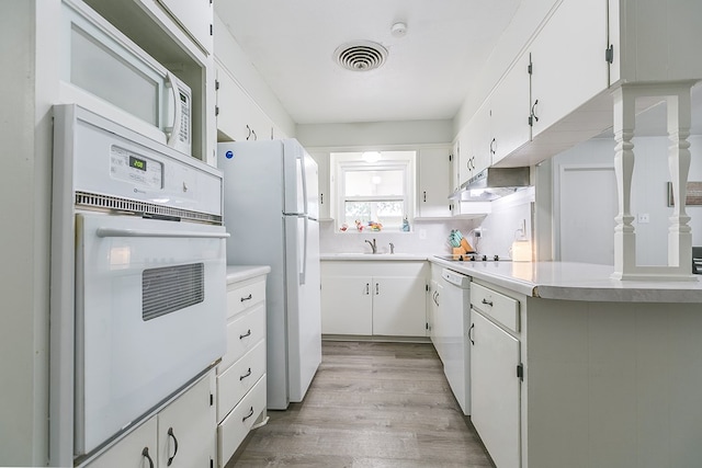 kitchen featuring white cabinetry, light wood-type flooring, white appliances, and decorative backsplash