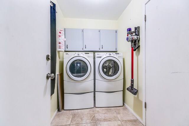 clothes washing area with cabinets and washer and clothes dryer