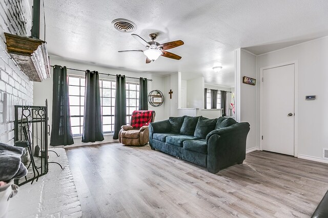 living room featuring a healthy amount of sunlight, a textured ceiling, a fireplace, and light hardwood / wood-style floors