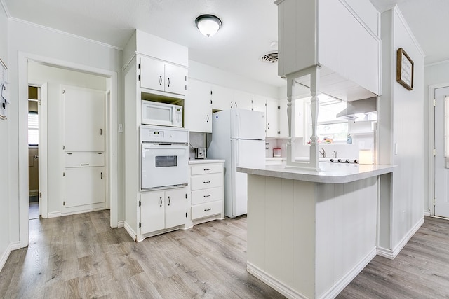 kitchen featuring white appliances, crown molding, white cabinetry, light hardwood / wood-style floors, and kitchen peninsula