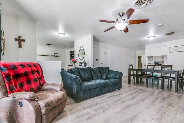 living room with ceiling fan, light hardwood / wood-style flooring, and a textured ceiling