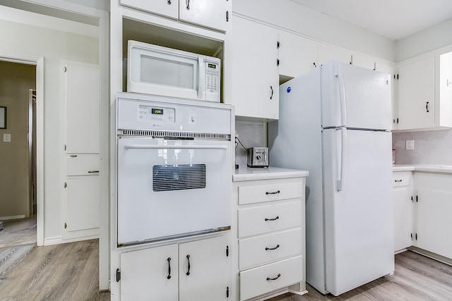 kitchen with light wood-type flooring, white cabinets, and white appliances