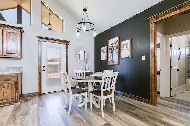 dining room with light wood-type flooring, baseboards, and lofted ceiling