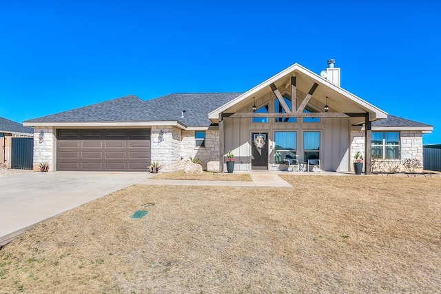 view of front of house featuring board and batten siding, driveway, an attached garage, a shingled roof, and stone siding