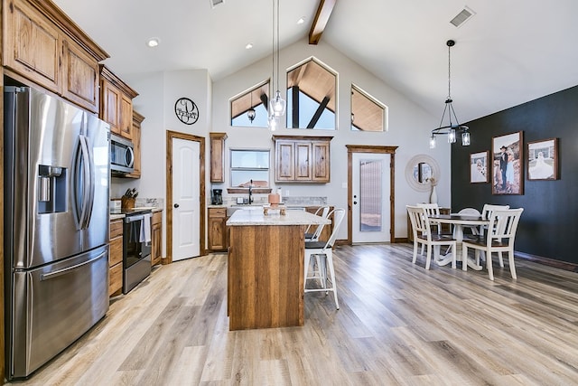 kitchen featuring appliances with stainless steel finishes, a kitchen breakfast bar, brown cabinetry, a center island, and visible vents