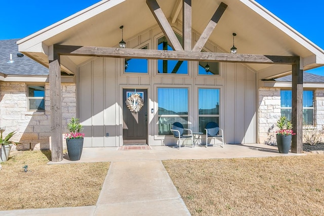 entrance to property featuring board and batten siding, roof with shingles, and stone siding